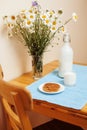 Simply stylish wooden kitchen with bottle of milk and glass on table, summer flowers camomile, healthy food moring Royalty Free Stock Photo