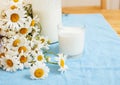 Simply stylish wooden kitchen with bottle of milk and glass on table, summer flowers camomile, healthy food moring Royalty Free Stock Photo