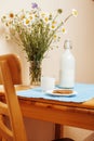 Simply stylish wooden kitchen with bottle of milk and glass on table, summer flowers camomile, healthy food moring Royalty Free Stock Photo