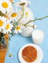 Simply stylish wooden kitchen with bottle of milk and glass on table, summer flowers camomile, healthy food morning