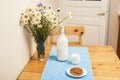 Simply stylish wooden kitchen with bottle of milk and glass on table, summer flowers camomile, healthy foog moring Royalty Free Stock Photo