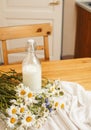 Simply stylish wooden kitchen with bottle of milk and glass on table, summer flowers camomile, healthy foog moring Royalty Free Stock Photo