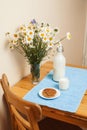 Simply stylish wooden kitchen with bottle of milk and glass on table, summer flowers camomile, healthy foog moring Royalty Free Stock Photo