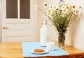 Simply stylish wooden kitchen with bottle of milk and glass on table, summer flowers camomile, healthy foog moring Royalty Free Stock Photo