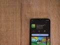 The Simpsons Tapped Out app play store page on smartphone on wooden background