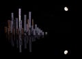 A simulated city skyline created with staples that form skyscrapers and the moon with a dark background and its reflection Royalty Free Stock Photo