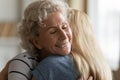 Elderly mother hugs grownup daughter enjoy moment showing attachment closeup