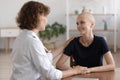 Sincere happy young bald woman listening to oncologist.