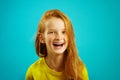 Sincere laughter of children girl with red hair on blue isolated. Happy child expresses a sincere emotion.