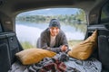 Sincerely smiling middle-aged man dressed in warm knitted clothes and jeans portrait in the cozy car trunk and with beautiful