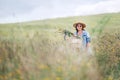 Sincerely smiling young Woman dressed jeans jacket and light summer dress walking by the high green grass meadow with basket and Royalty Free Stock Photo