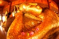 Elderly Thai female Buddhist Gold leaf is being installed on the replica of the reclining Buddha image.
