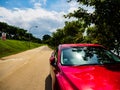 SINGAPORE - 25 DEC 2019 - Shiny red car parked beside a motorway next to a nature park / nature reserve on a sunny day. To Royalty Free Stock Photo