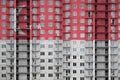 Singapore flag depicted in paint colors on multi-storey residental building under construction. Textured banner on brick wall