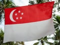 Singapore flag waving on wind on sky background. Singapore Flag Day. Flag of Singapore fluttering in sunny rays high. Celebration