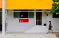 Typical local heartland neighbourhood; Singapore flag hung outside apartment.. Asian woman in face mask walking past ground floor