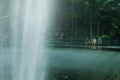 People with face masks relaxing at Rain Vortex fountain at Changi Airport Jewel. High speed capture of water