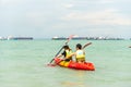Singapore East Coast Park Beach. Two Asian sportsmen sportswomen canoeing out to the sea. Teamwork in progress.