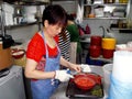 A woman cuts hot peppers in a restaurant kitchen of a typical Singapore food court or Hawker