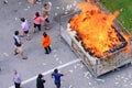 Singapore Sep2021 People burning throwing joss paper money into metal cage as offerings during 7th month Hungry Ghost Festival.