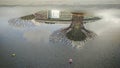 a pool of water on a road reflecting the buildings in Garden By The Bay