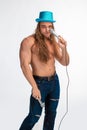 Singer bodybuilder shirtless with long hair in a blue hat with a microphone