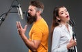 Singer duet couple is performing a song with a microphone while recording in a music studio. Royalty Free Stock Photo