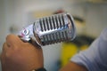 singer hand holding silver chrome vintage microphone
