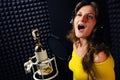 Singer in the music studio, close-up. Woman sings into a microphone on a black background. Professional female vocalists with blue Royalty Free Stock Photo