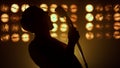 Singer performing song firely on stage closeup. Silhouette unknown man performer