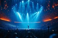 Singer performs a musical concert on stage in a huge packed stadium hall