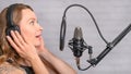 Singer with a tattoo sings rock music in the studio into a microphone, musician and treble vocals Royalty Free Stock Photo