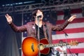 Singer Tom Higgenson of Plain White Ts holds guitar and talks in microphone on stage