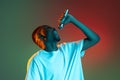 Young african man singing with microphone on neon gradient background. Concept of emotion, action, facial expression. Royalty Free Stock Photo