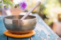 Singing bowl on a rustic wooden table with flowers, zen, outdoors Royalty Free Stock Photo