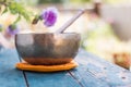 Singing bowl on a rustic wooden table with flowers, zen, outdoors Royalty Free Stock Photo