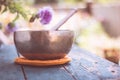 Singing bowl on a rustic wooden table with flowers, zen, outdoors Royalty Free Stock Photo