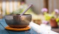 Singing bowl on a rustic wooden table with flowers, zen, outdoors