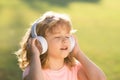 Singing children. Stylish teen boy listening music in headphones and singing against green grass summer background Royalty Free Stock Photo