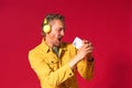 Singing handsome man enjoying his favorite song using phone and wireless headphones wearing jeans yellow jacket isolated Royalty Free Stock Photo