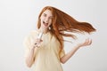 Singing her heart out. Portrait of cool confident emotive young woman with ginger hair that waves on air, holding