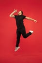 Full length portrait of young successfull high jumping man gesturing isolated on red studio background Royalty Free Stock Photo