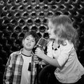 Singing little children with a microphone on a rack against a bl Royalty Free Stock Photo