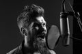 Singing man in a recording studio. Expressive bearded man with microphone. Closeup portrait. Royalty Free Stock Photo