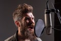 Singing man in a recording studio. Expressive bearded man with microphone. Closeup portrait. Royalty Free Stock Photo