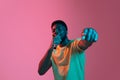African young man& x27;s portrait on pink studio background in neon. Concept of human emotions, facial expression, youth