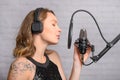 Singing and working in a studio with a microphone. A girl sings, rehearses in a recording studio