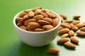 Single almond in a white ceramic bowl on green background, promoting healthy eating