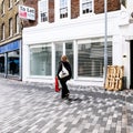 Single Anonymous Woman Walking Past A Closed High Street Retail Business Shop During COVID-19