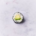 Single avocado sushi maki on a marble surface